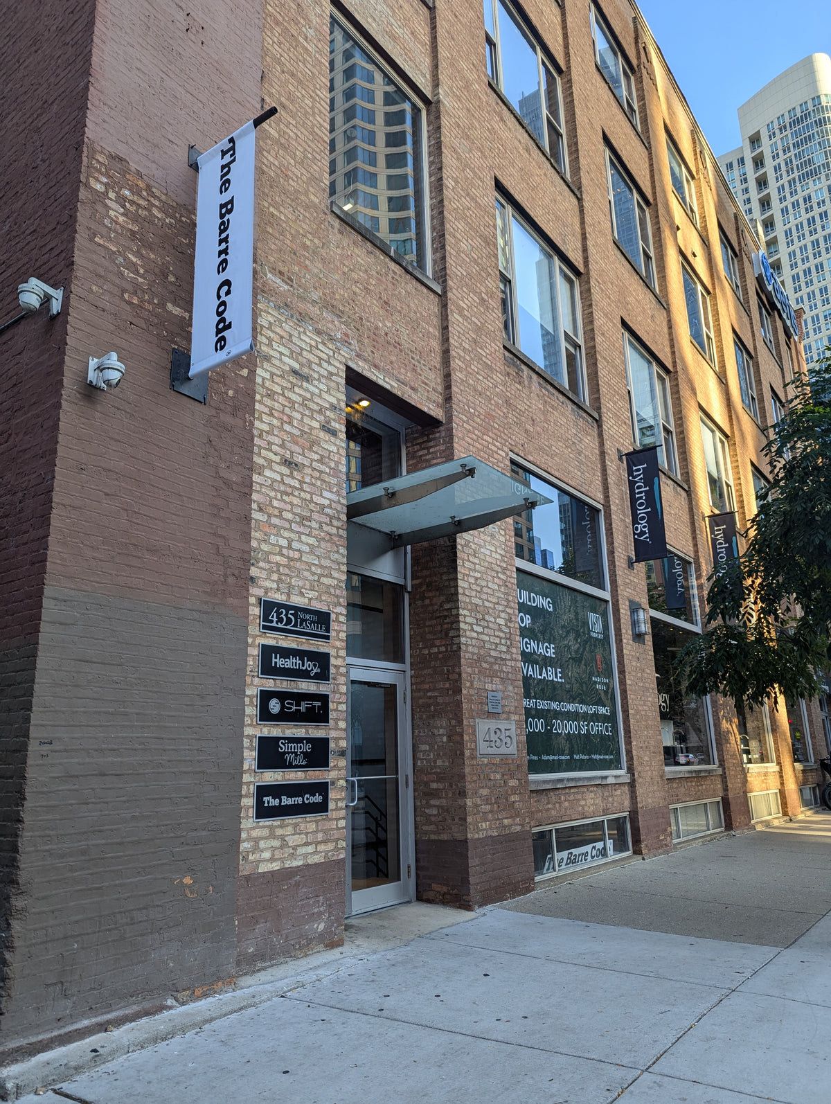 The front door to the large Chicago pink brick building located at 435 N La Salle Dr is shown here with signage for The Barre Code. This address is located in River North and the cross street is Hubbard.
